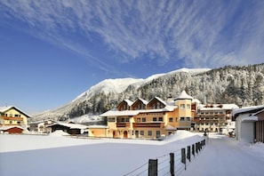 Ein schneebedecktes Bergresort mit Chalets, bewölktem Himmel und einer Skipiste im Vordergrund.