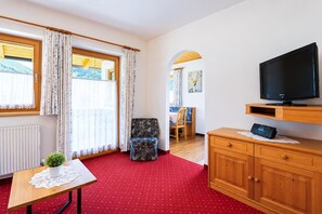 A room with a television, wooden cabinet, and a chair. - Apartment near the lake (Achenkirch)