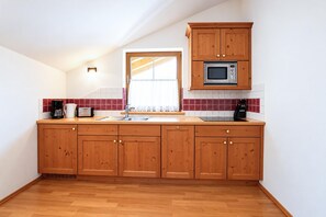 A kitchen with wooden cabinets, a microwave, a coffee maker, and a toaster. - Apartment near the lake (Achenkirch)