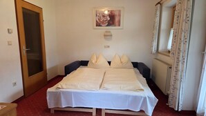 Une chambre à coucher avec un lit, une porte, un radiateur et une fenêtre avec des rideaux.