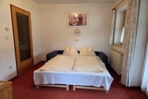 Ein Schlafzimmer mit einem Bett, einer Tür, einem Heizkörper und einem Fenster mit Vorhängen.