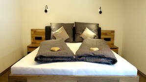A neatly made bed with a white mattress and dark patterned bedding, flanked by wooden headboards and nightstands. - Panoramic View Suite on the Kaunergrat (Kaunerberg)