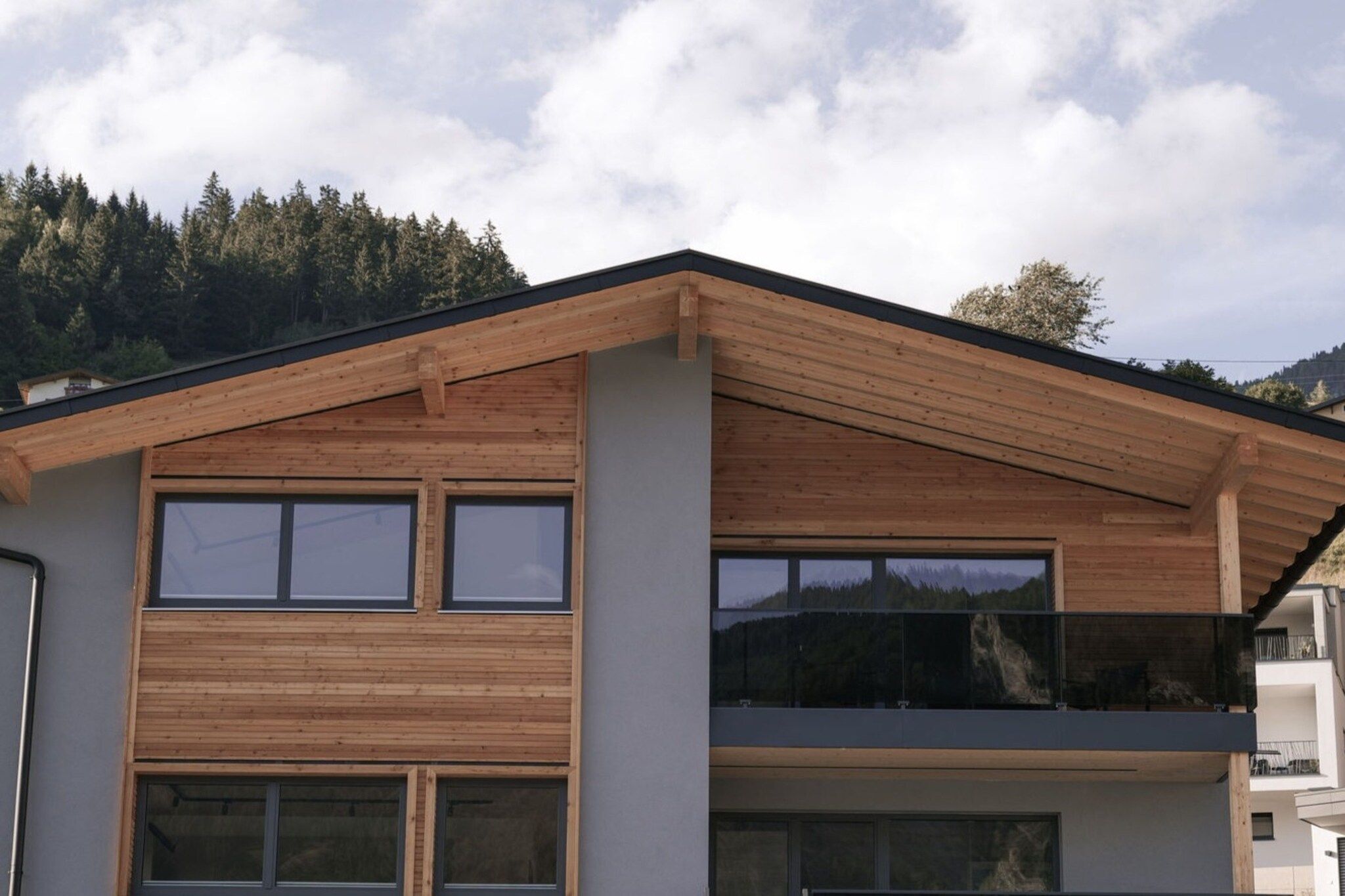 Un edificio moderno su due piani con tetto spiovente, ampie finestre e un balcone.