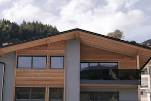 Ein modernes, zweistöckiges Gebäude mit schrägem Dach, großen Fenstern und einem Balkon.