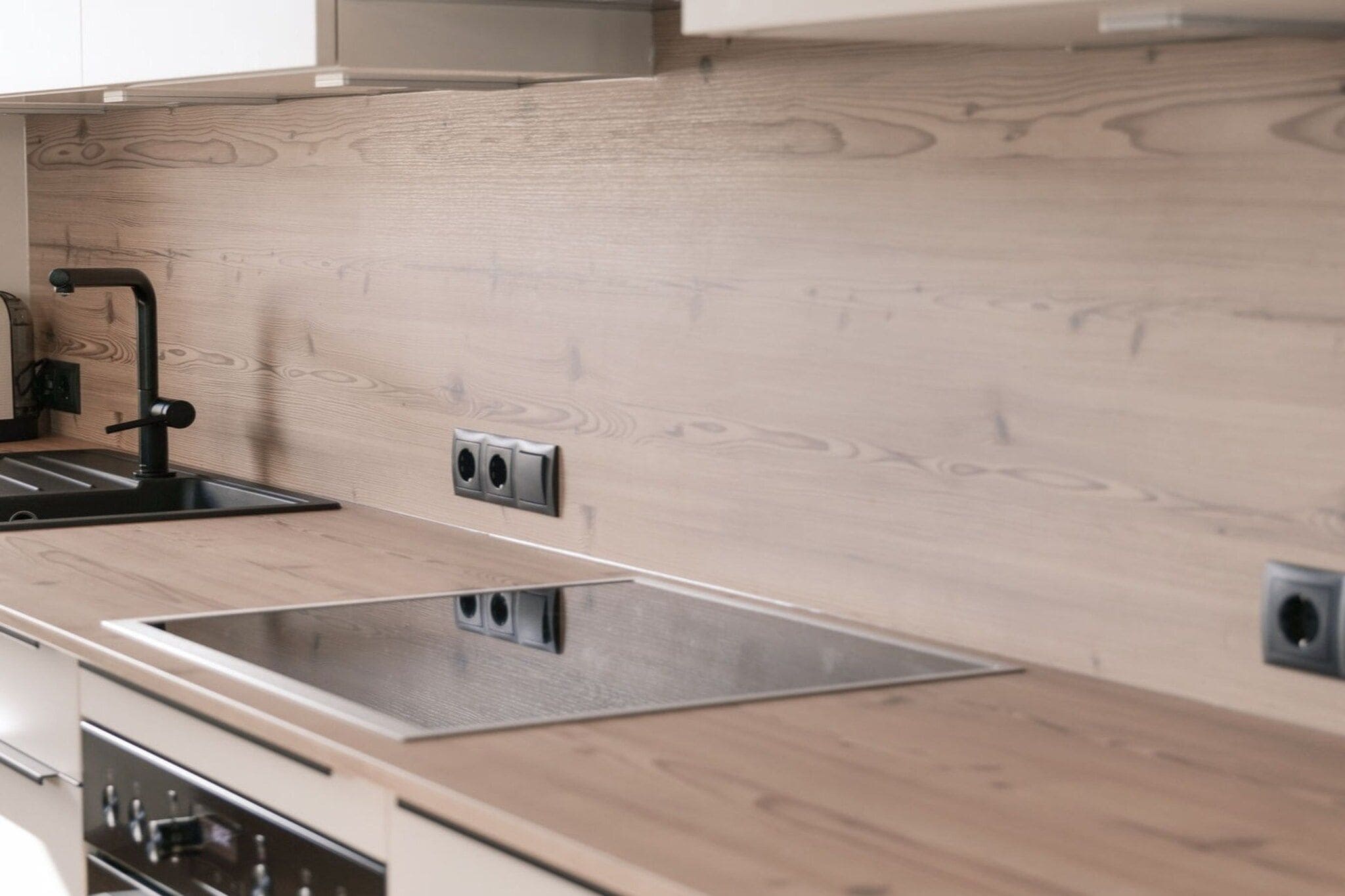 Une cuisine moderne avec un revêtement mural en bois, un évier en acier inoxydable et des appareils électroménagers intégrés.