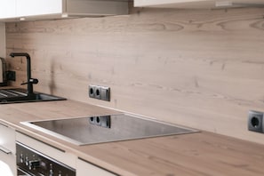 Eine moderne Küche mit Holzverkleidung, einer Edelstahlspüle und eingebauten Geräten.