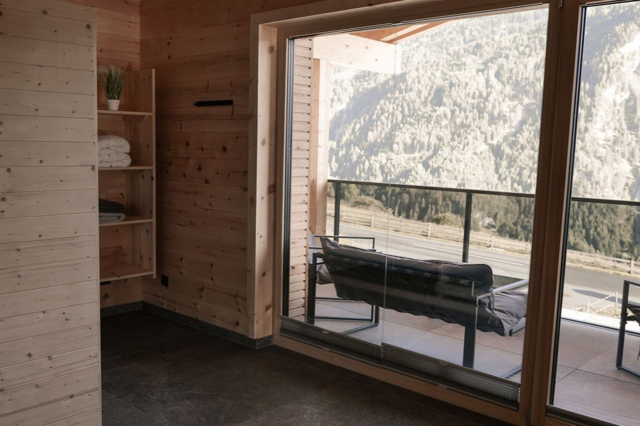 Un intérieur en bois avec un banc et une vue sur une montagne enneigée.