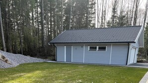 En bostadsfastighet med en välskött gräsmatta, ett trädäck och ett hus med ett tegeltak.