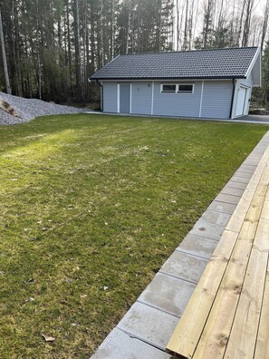 Ein Wohnhaus mit gepflegtem Rasen, einer Holzterrasse und einem Dach mit Ziegeldeckung.