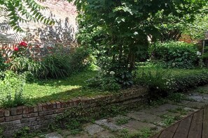 Ein Garten mit einer Ziegelmauer, verschiedenen Pflanzen und einer Holzterrasse.