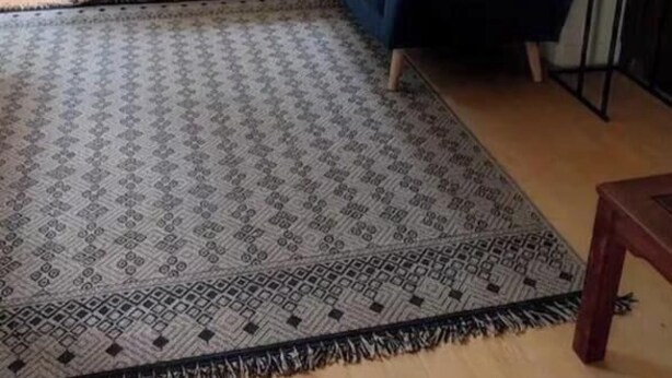 Una habitación con cama, un sofá azul, un tapiz estampado y una ventana con cortinas.