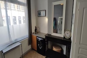 Una cocina funcional con lavadora, un lavamanos y un reloj en la pared.