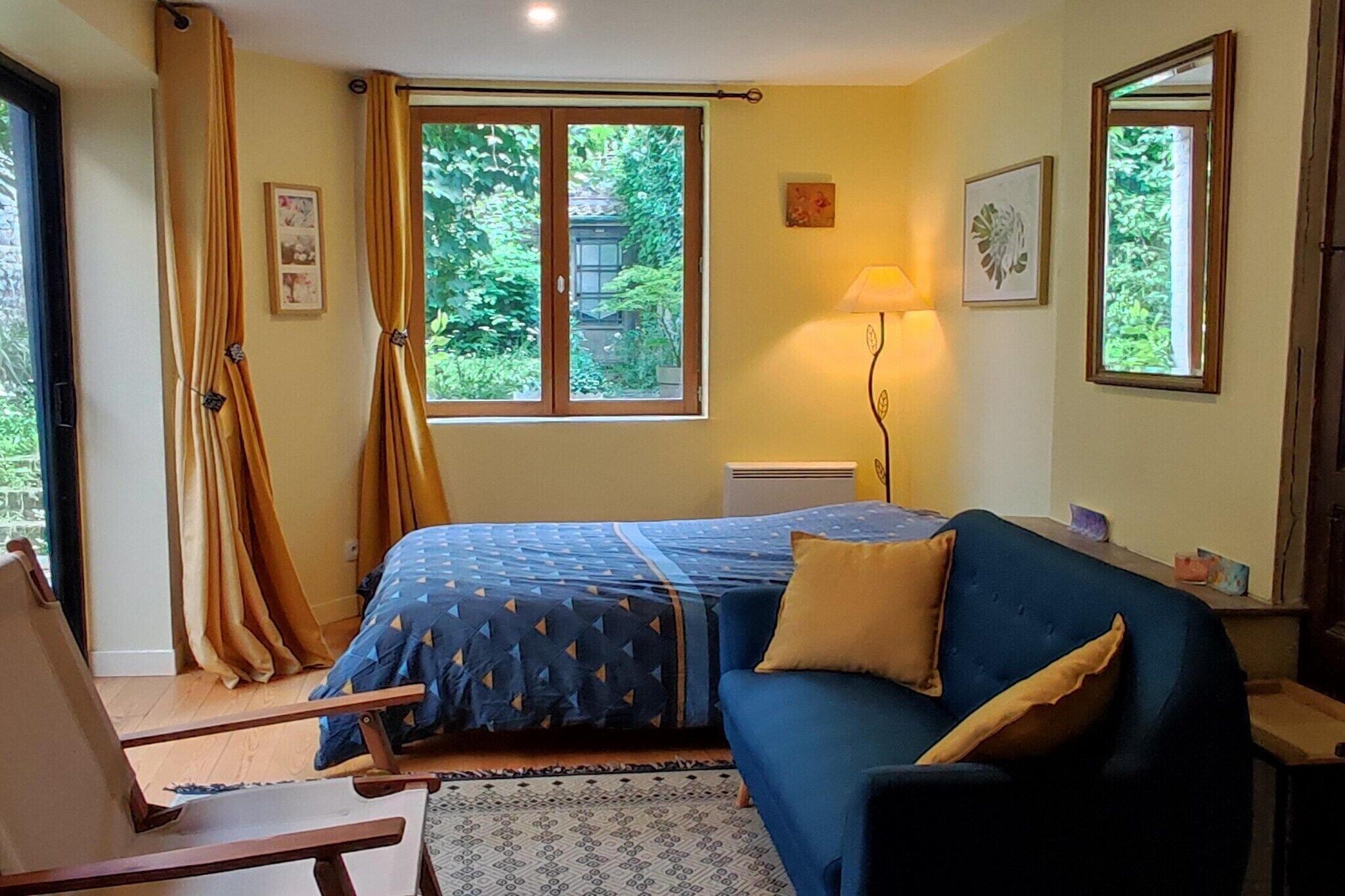 A bedroom with a bed, a chair, a lamp, and a window with curtains.