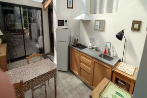 Eine kompakte Küche mit Kühlschrank, Mikrowelle, Herd, Spüle und einem kleinen Essbereich mit Tisch und Stuhl.