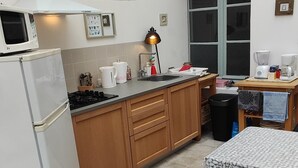 Una cocina compacta con microondas, estufa, lavaplatos y un pequeño comedor con mesa y sillas.