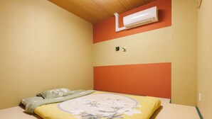 Ein Schlafzimmer mit einem Bett, einer Wandklimaanlage und einer kleinen Pflanze an der Wand.