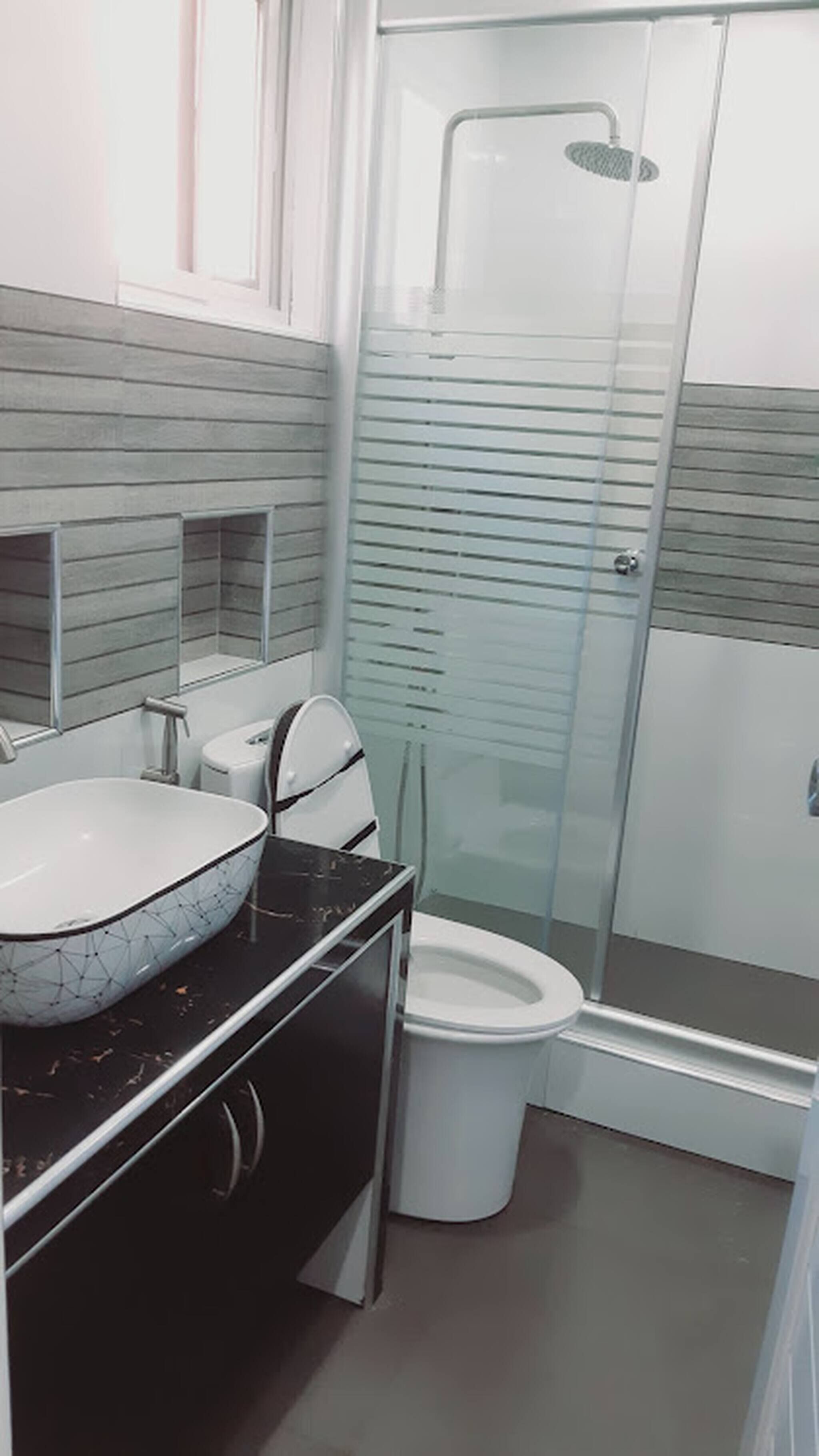 Un bagno moderno con cabina doccia in vetro, un WC bianco e un lavabo in marmo.