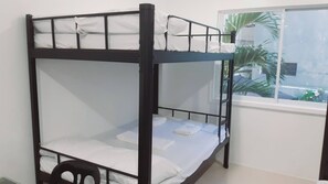 Ein Etagenbett mit weißer Bettwäsche und einem Fenster mit Blick auf Grün.