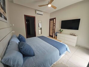 Ein Schlafzimmer mit Bett, Deckenventilator, Fernseher und Kommode.