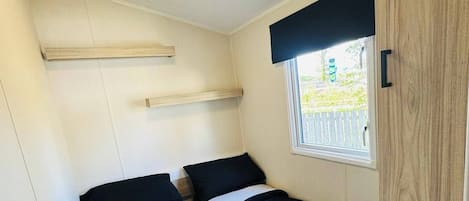 A compact room with two beds, a window with a view, and a ceiling light.