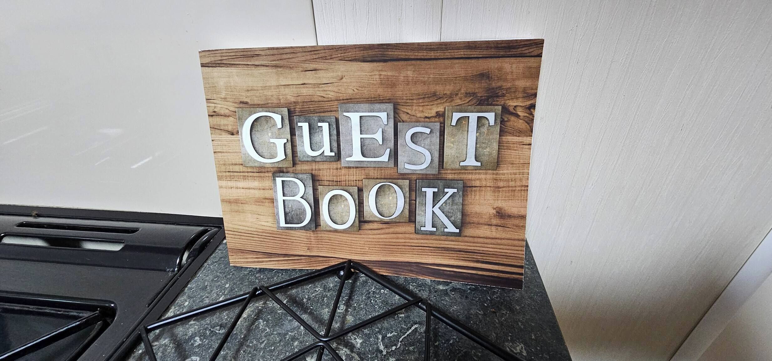 A sign with the words 'Guest Book' on a wooden background.