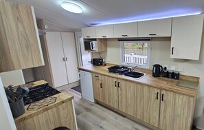 Une petite cuisine équipée d’une cuisinière à gaz, d’un four à micro-ondes et d’un petit évier.