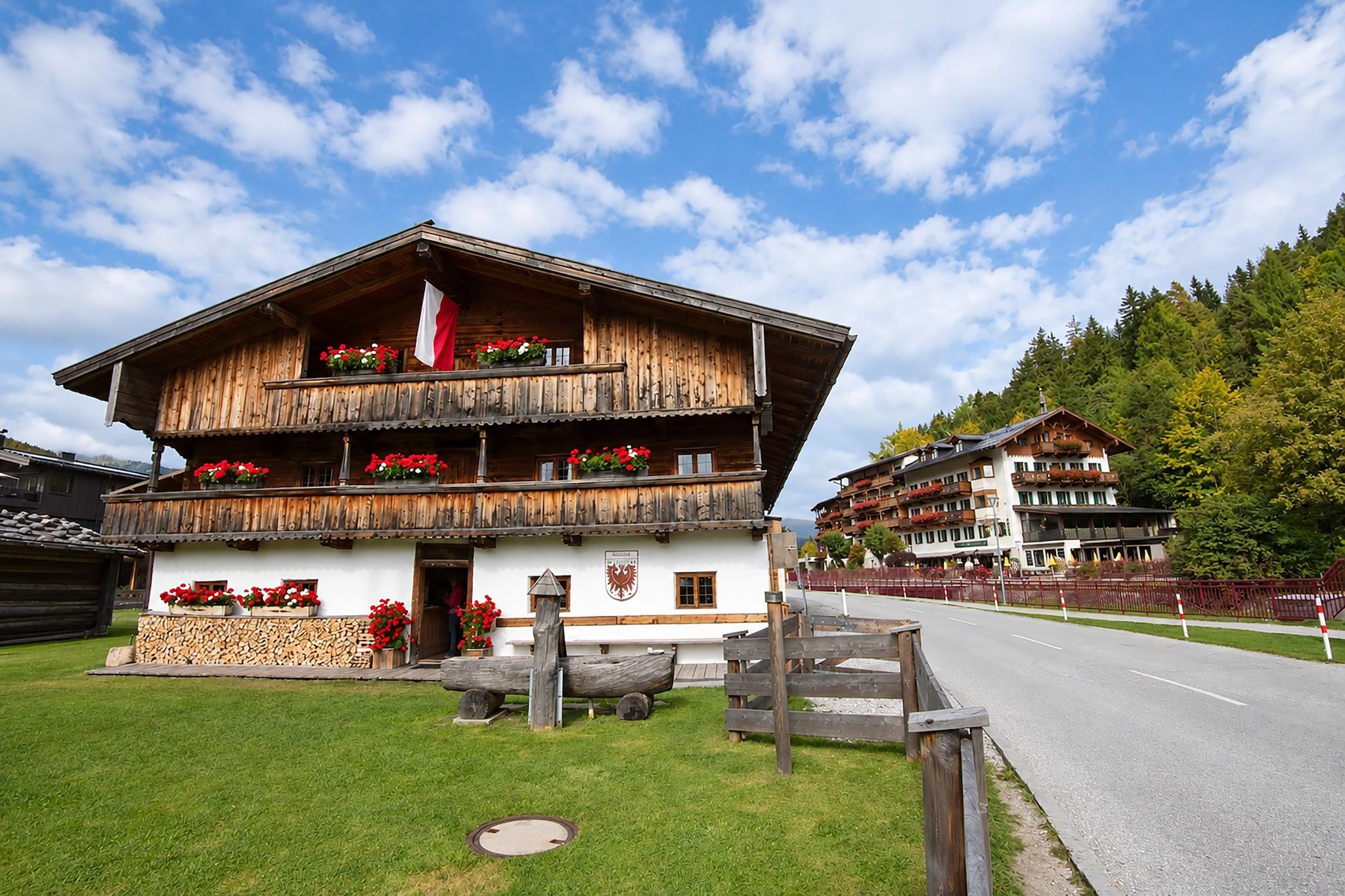 A traditional wooden chalet with a balcony, a flag, and flower boxes.