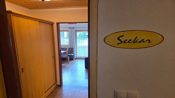 Un pasillo que conduce a un comedor con un divisor corredero y un cartel en la pared que dice 'Seebach'.