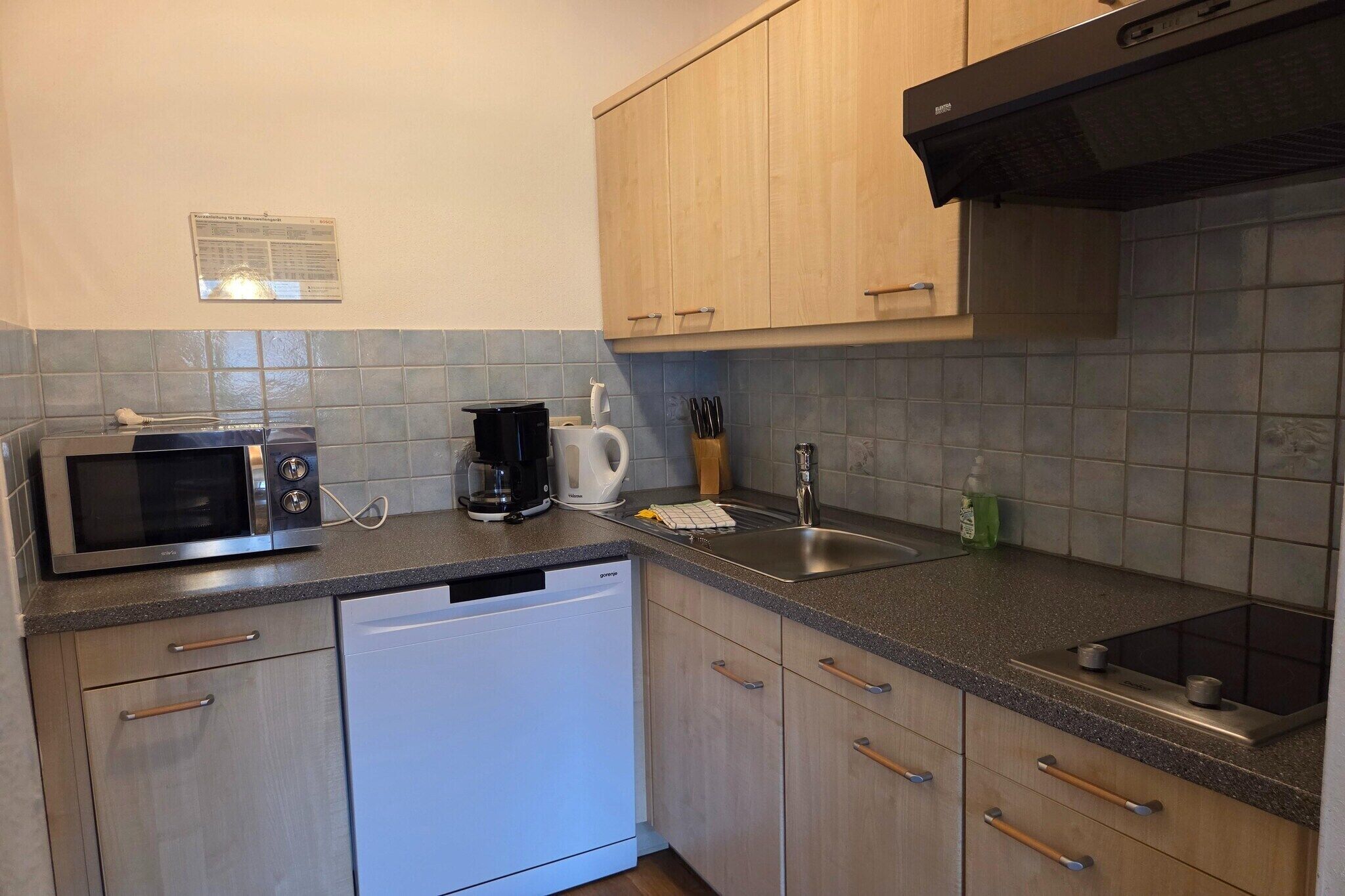 Una cocina equipada con microondas, cafetera, lavabo y lavavajillas.