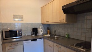 Una cocina equipada con microondas, cafetera, lavabo y lavavajillas.