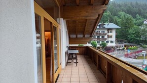 En balkon med gelænder af træ, et bord og stole.