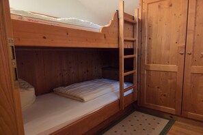 Ein Stockbett mit einer Leiter, ein Holzschrank und ein gemustertes Teppich.