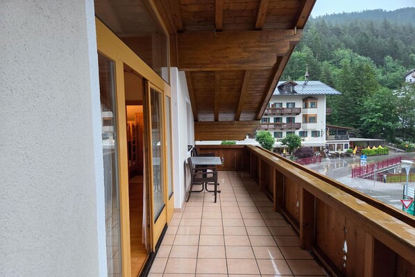 A balcony with a wooden railing, a table, and chairs.