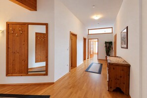 A hallway with wooden flooring, a wooden cabinet, and a mirror on the wall. - Alpine holiday apartment near a lake (Achenkirch)