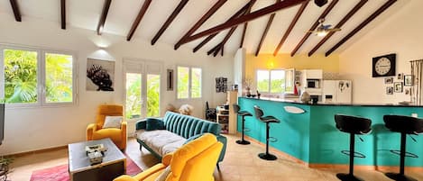 A spacious living area with a sofa, armchairs, a coffee table, and a kitchen area with a bar.