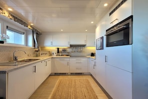 A modern kitchen with white cabinets, stainless steel appliances, and a granite countertop. - Coastal Comfort Middelkerke (MIDDELKERKE)