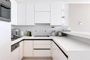Eine moderne Küche mit weißen Schränken, einem Backofen, einer Kaffeemaschine, einem Mixer und einem Toaster.