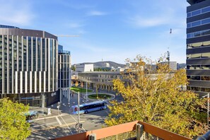 A modern building with a curved facade and a bus stop in front. - City-Edge 1-Bed Apartment with Pool Access (City)