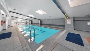 Piscina interna com pistas demarcadas, grades de segurança e posto de salva-vidas.