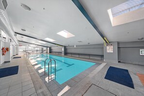 Ein Hallenbad mit deutlich markierten Bahnen, Sicherheitsgeländern und einem Rettungsschwimmerstand.
