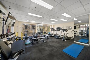 A gym with various exercise equipment, including treadmills, weight machines, and free weights. - Stylish 2-Bed Stay with Pool & Parking (City)