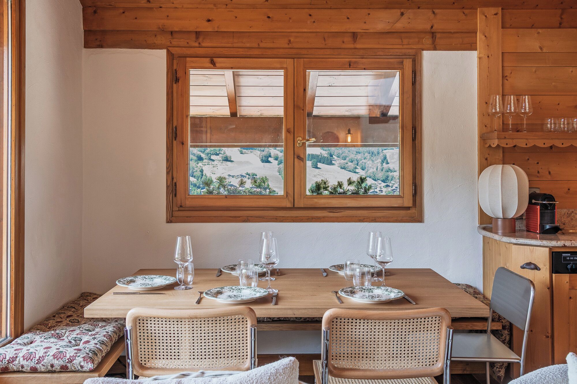 A wooden dining table with a view of a snowy landscape through a window.