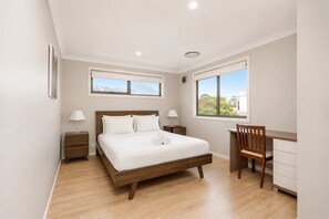 A bedroom with a bed, bedside tables, a desk, and a chair. - Charming 4-Bed Getaway with Pool & Garden Oasis (Curtin)