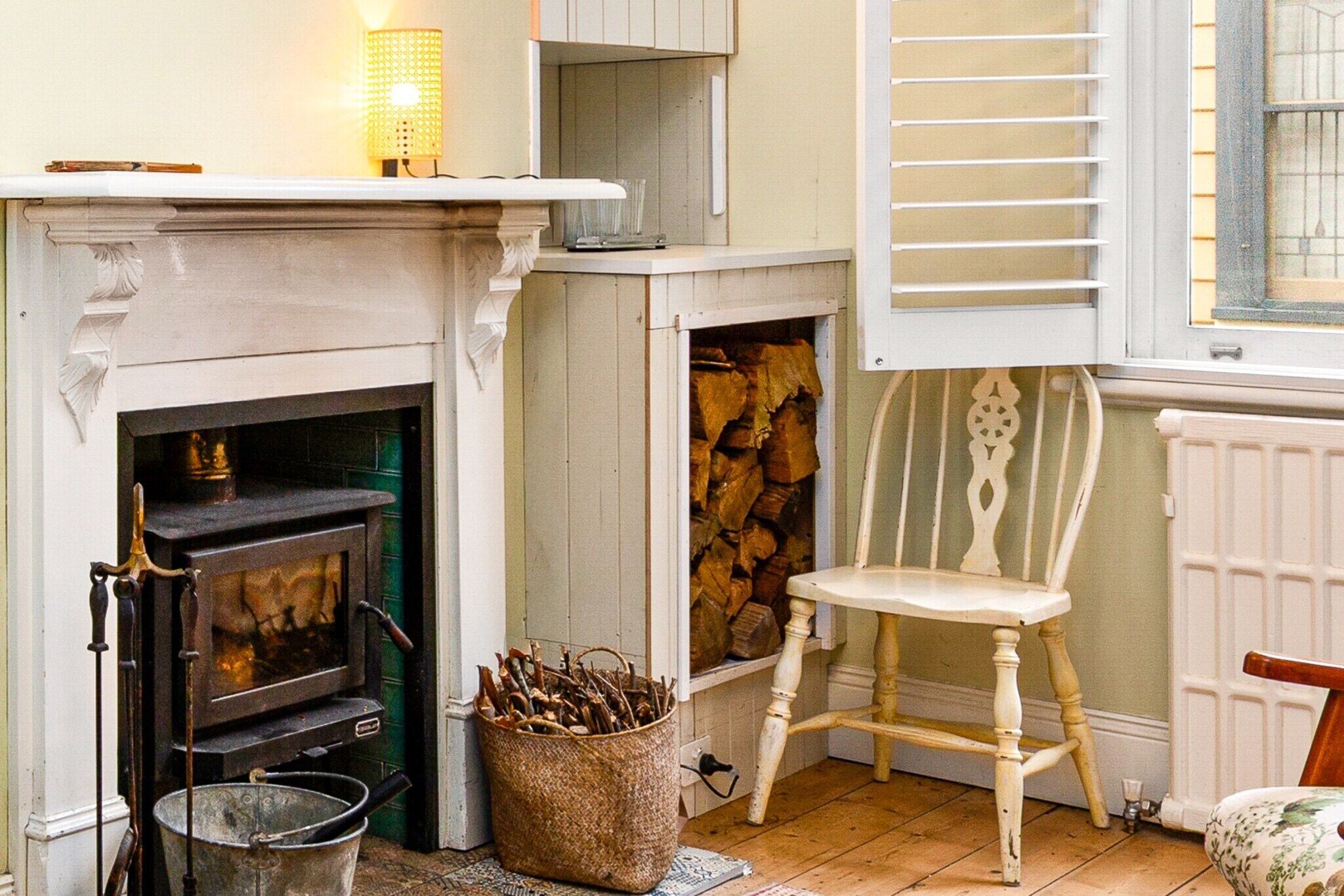 A cozy room with a fireplace, a chair, and a basket of firewood.