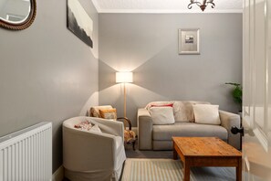 Ein Wohnzimmer mit Sofa, Sesseln, einer Lampe und einem kleinen Tisch.