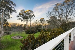 A garden with various trees and shrubs, a grassy area, and a white railing.