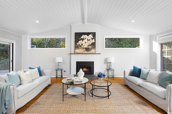 A modern living room with two sofas, a fireplace, and artwork above it.