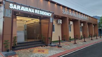 Edificio Saravana Residency con fachada moderna, amplio acceso de vidrio y zona de entrada pavimentada con diseño decorativo.