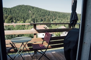 A balcony with a table and chairs, overlooking a forested hillside. - Le Pic Noir, View of the Lake and Mountains (Gérardmer)
