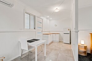 Une cuisine compacte comprenant une table à manger, un réfrigérateur et une horloge murale.